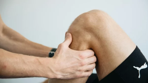 A therapist providing remedial massage for injury recovery on a client’s knee to relieve pain and improve mobility.