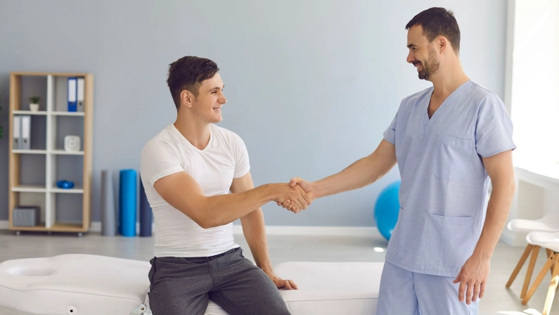 A satisfied patient shaking hands with an osteopath Gold Coast specialist after a successful chronic pain relief osteopathy session.